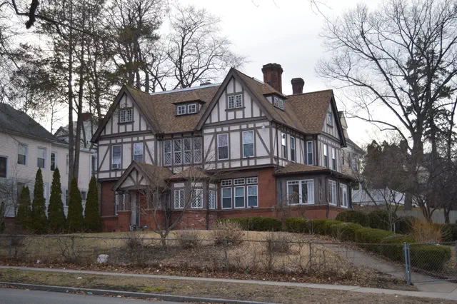 Tudor Revival (1890-1945) brought English late-medieval and early-Renaissance forms to American suburbs — half-timbered gables, casement windows, Cotswold cottages. Massachusetts's western suburbs have substantial inventories.